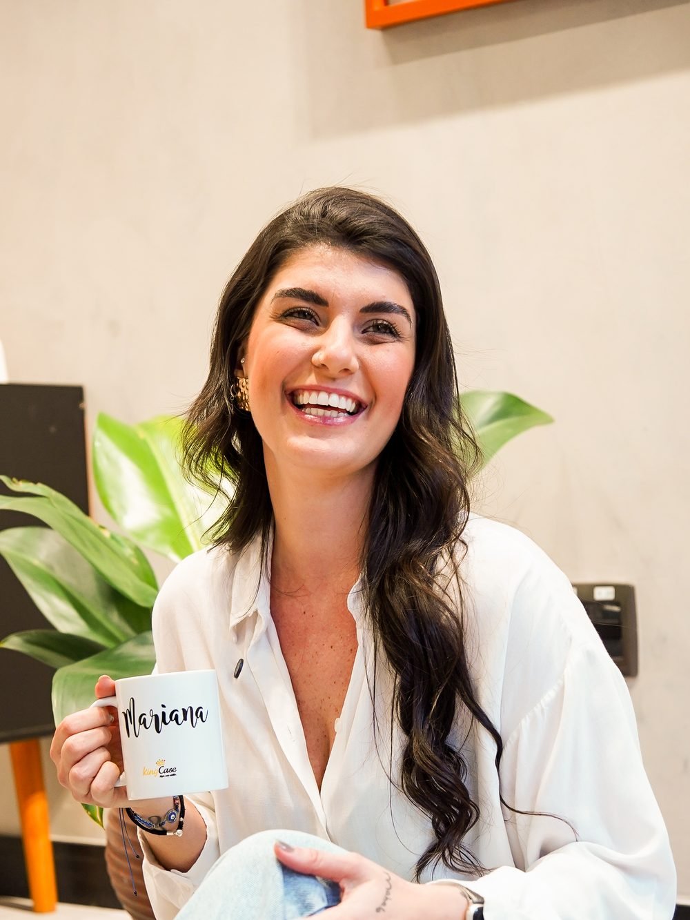 Mari rindo no escritório, café na mão