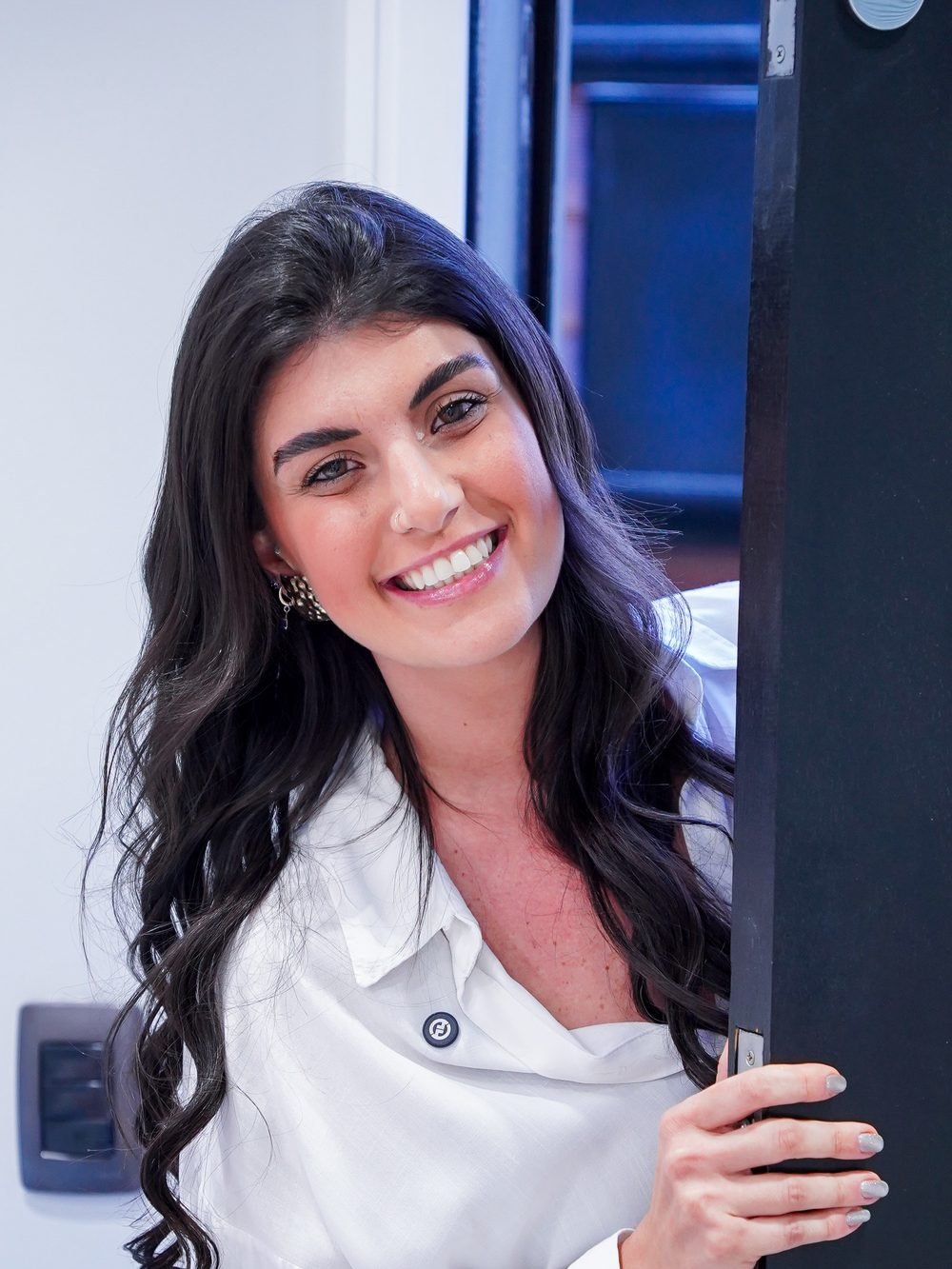 Mari Abumussi sorrindo, apoiada na porta