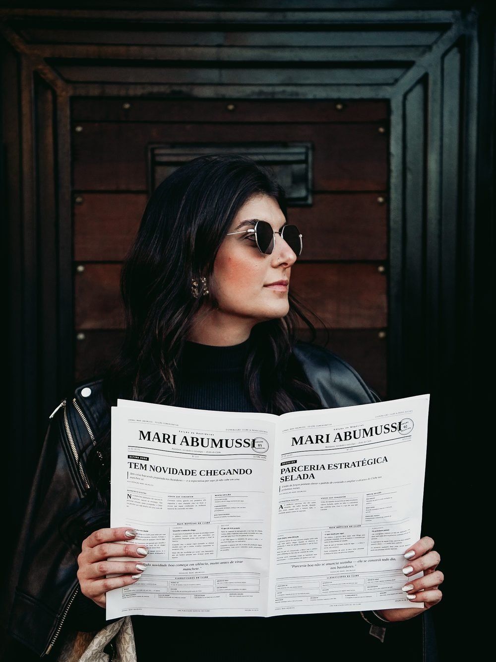 Mari de óculos escuros segurando o jornal aberto