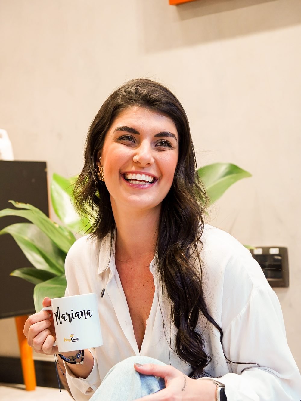 Mari Abumussi rindo no escritório, café na mão
