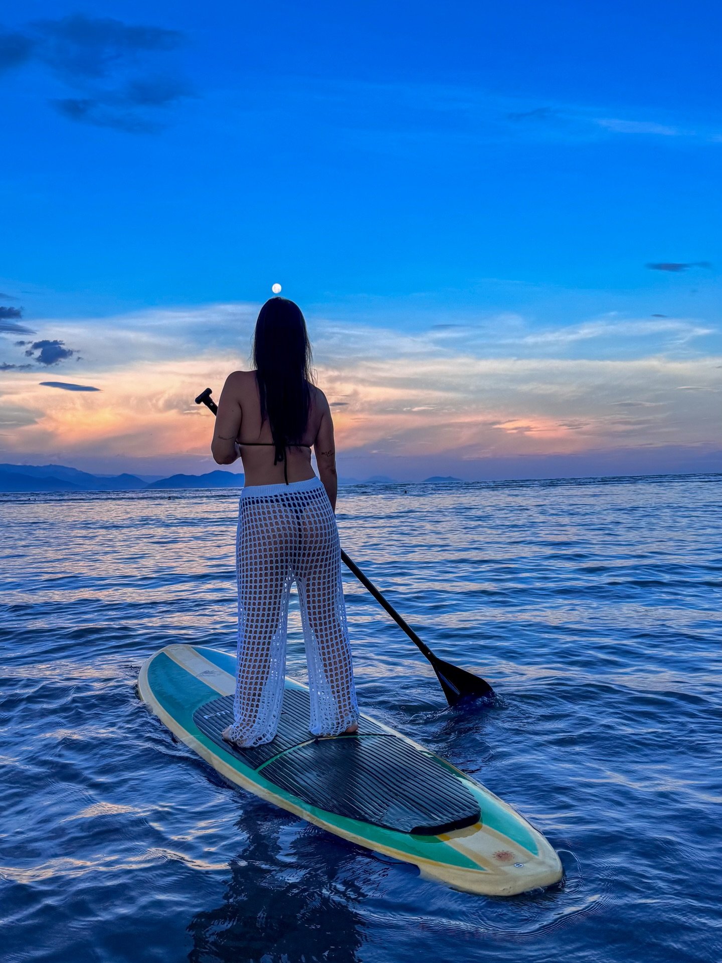 Mari remando de SUP no pôr do sol